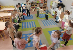 Dzieci tańczą ze swoimi misiami w kole.