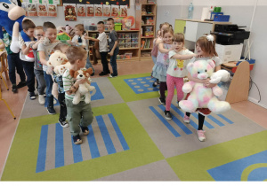 Dzieci tańczą z misiami w pociągu.