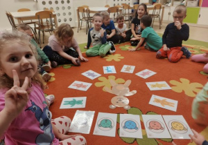 Dzieci siedzą w kole, w środku leżą obrazki z misiami.