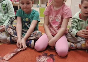 Dzieci siedzą na dywanie przed nimi leżą misie ułożone z części.