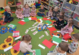 Dzieci siedzą na dywanie przed nimi leżą misie ułożone z części.