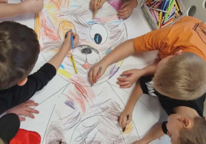 Przedszkolaki kolorują dużego misia.