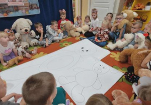Dzieci siedzą w kole, w środku duże narysowane misie.