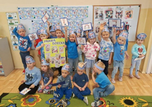 Grupa młodsza pozuje do zdjęcia, dzieci trzymają plakat o prawach dziecka i obrazki tematyczne.