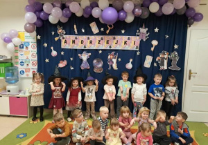 Grupa młodsza pozuje do zdjęcia na tle tematycznej dekoracji.