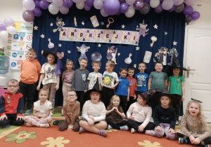 Grupa starsza pozuje do zdjęcia na tle tematycznej dekoracji.