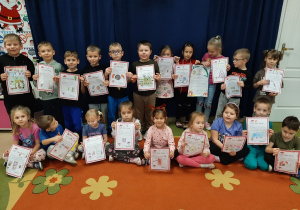 Dzieci ustawione na granatowym tle pozują trzymając w rękach listy do Mikołaja.