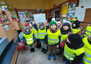 W urzędzie pocztowym. Dzieci pozują do fotografii, chłopiec trzyma w rękach kopertę z listami do Mikołaja