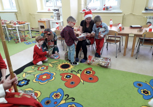 Dzieci z rodzicami rozpakowują prezenty.