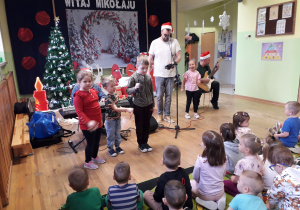 Dzieci muzykują wspólnie z muzykami podczas świątecznej audycji muzycznej.