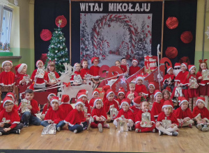 Dzieci pozują do wspólnego zdjęcia z Mikołajem. W tle dekoracja.