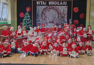 Dzieci pozują do wspólnego zdjęcia z Mikołajem. W tle dekoracja.