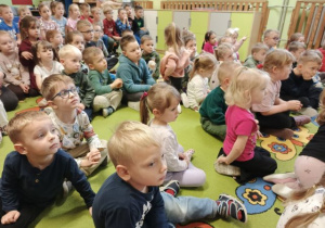 Dzieci siedzą i słuchają kolęd.