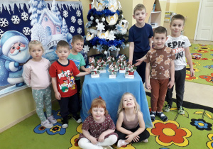 Dzieci pozują na tle wykonanych stroików świątecznych.