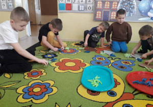 Zabawa matematyczna "Dodawanie z reniferem." Chłopcy przypinają na sylwecie renifera spinacze zgodnie z działaniem dodawania.