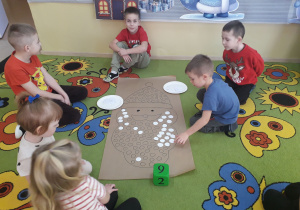 Zabawa matematyczna "Mikołaj". Dzieci rzucają kostką, układają tyle białych kropek ile pokazała kostka.