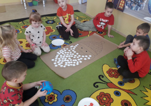 Zabawa matematyczna "Mikołaj". Dzieci rzucają kostką, układają tyle białych kropek ile pokazała kostka.