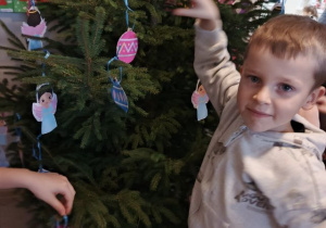 Chłopiec wiesza ozdobę na choince.