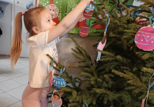 Dziewczynka wiesza ozdobę na choince.