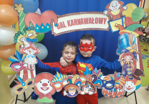 Dwoje chłopców strojach superbohaterów pozuje w fotobudce.