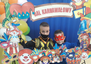 Dwoje chłopców strojach superbohaterów pozuje w fotobudce.