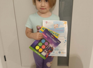 Dziewczynka trzyma dyplom i nagrodę