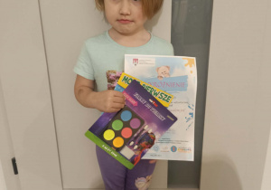 Dziewczynka trzyma dyplom i nagrodę