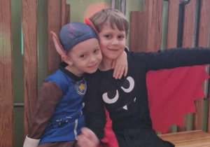 Dzieci w przebraniach siedzą na ławce