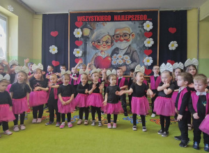 Dzieci stoją na tle dekoracji i śpiewają piosenkę.