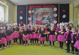 Wszystkie dzieci śpiewają piosenkę. W tle dekoracja.