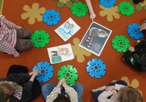 dzieci siedzą w kole na dywanie oglądają plakaty dityczące zanieczyszczenia powietrza.