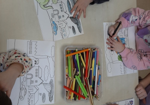 Dzieci siedzą przy stoliku i kolorują obrazki przedstawiające środowisko z czystym i zanieczyszczonym powietrzem - kolejne ujęcie.