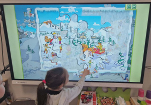 Dzieci układają puzzle z wykorzystaniem ekranu.