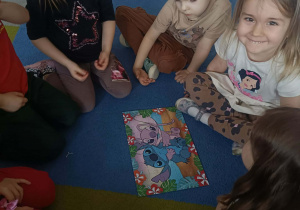 Dzieci układają na dywanie puzzle.