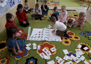 Dzieci na dywanie podczas zabawy matematycznej "Zwierzęta Lodowej Krainy", przeliczają i układają sylwety zwierząt zgodnie z podaną liczbą.