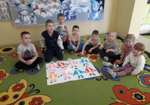 Dzieci na dywanie prezentują pracę plastyczną Inuita.