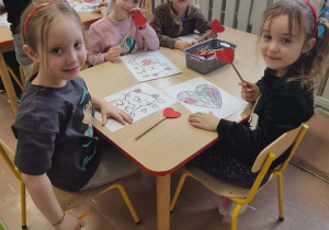 Dzieci przy stoliku podczas kolorowania walentynek