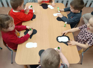 Dzieci przy stoliku wykonują pracę plastyczną - pingwina