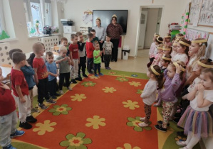 Chłopcy stoją naprzeciwko dziewczynek i składają życzenia z okazji Dnia Kobiet.