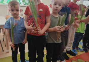 Chłopcy trzymają kwiatki, które wręczą dziewczynkom.