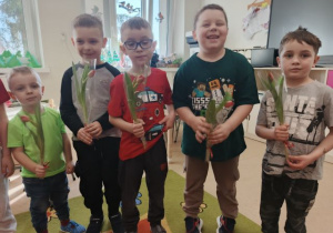 Chłopcy trzymają kwiatki, które wręczą dziewczynkom.