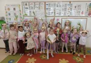 Dziewczynki pozują do zdjęcia i trzymają kwiatki.