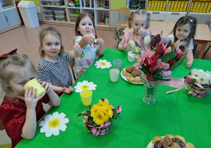 Dziewczynki siedzą przy stole ze słodkościami
