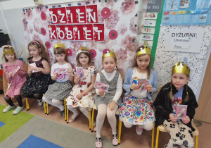 Dziewczyny siedzą na tle dekoracji z prezentami