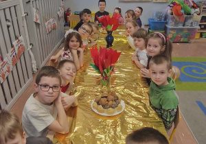 Dzieci siedzą przy stole ze słodkościami