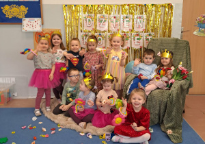 Grupa dzieci młodszych pozuje do zdjęcia na tle dekoracji