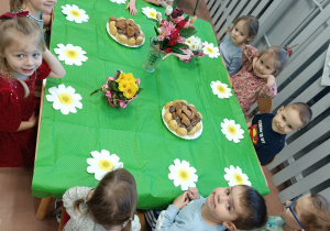 Dzieci siedzą przy stole ze słodkościami