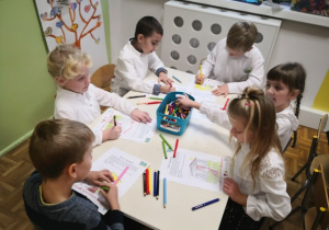 Dzieci siedzące przy stolikach i kolorujące obrazki