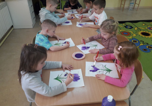 Dzieci podczas malowania farbami sylwet krokusów.