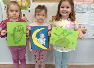 Dzieci stoją i prezentują prace na konkurs plastyczny